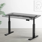 Black height-adjustable standing desk frame set up in a bright, modern home office space.
