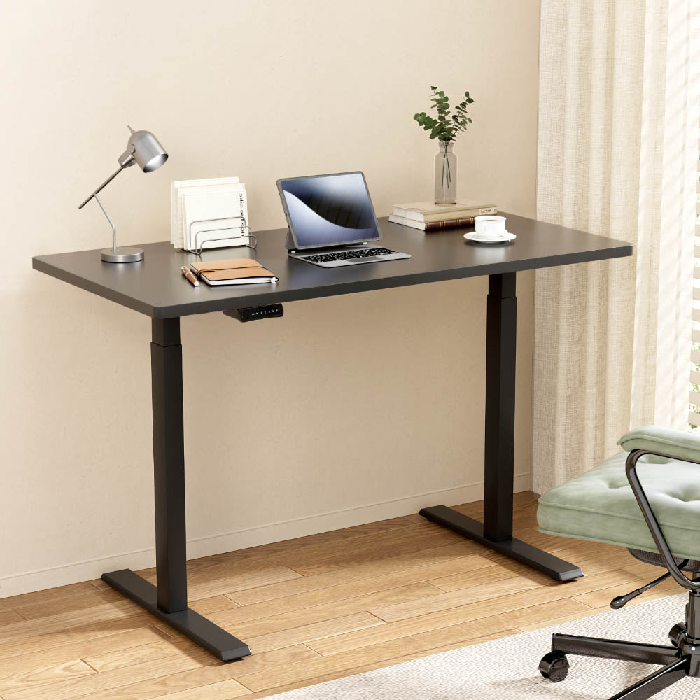 Black Studio height-adjustable standing desk set up in a bright, modern home office workspace.