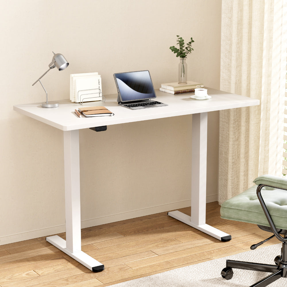 White Studio height-adjustable standing desk set up in a bright, modern home office workspace.