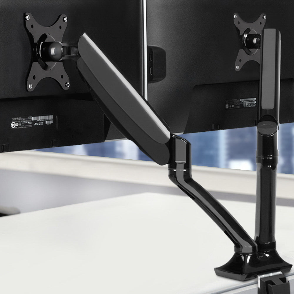 Black Studio dual gas-spring monitor arm holding two computer screens on a clean desk setup.
