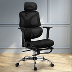 Black ergonomic mesh desk chair with footrest set up in a modern home office space with timber flooring.