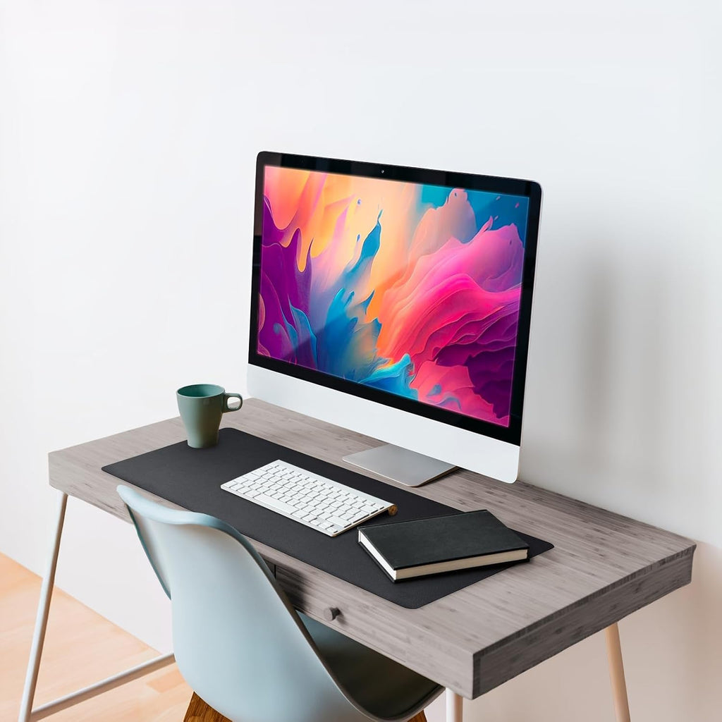 Black Studio premium leather desk mat protecting a modern wooden office desk beneath a computer monitor.