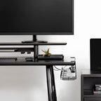 Under-desk view of the black cable management tray securely hiding power bricks and cords on a modern standing desk.