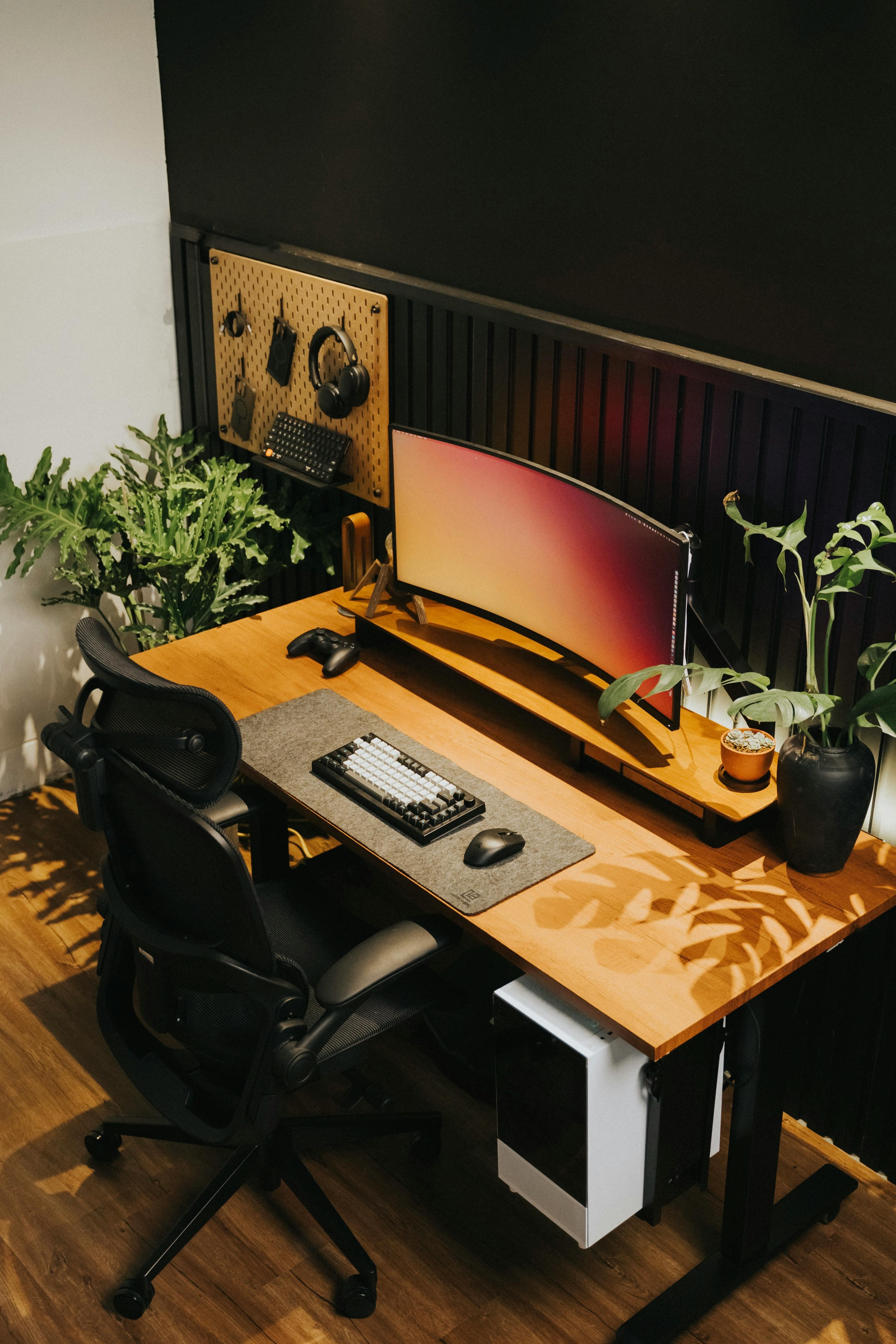 Modern home office desk setup with a computer monitor, keyboard, and plants.