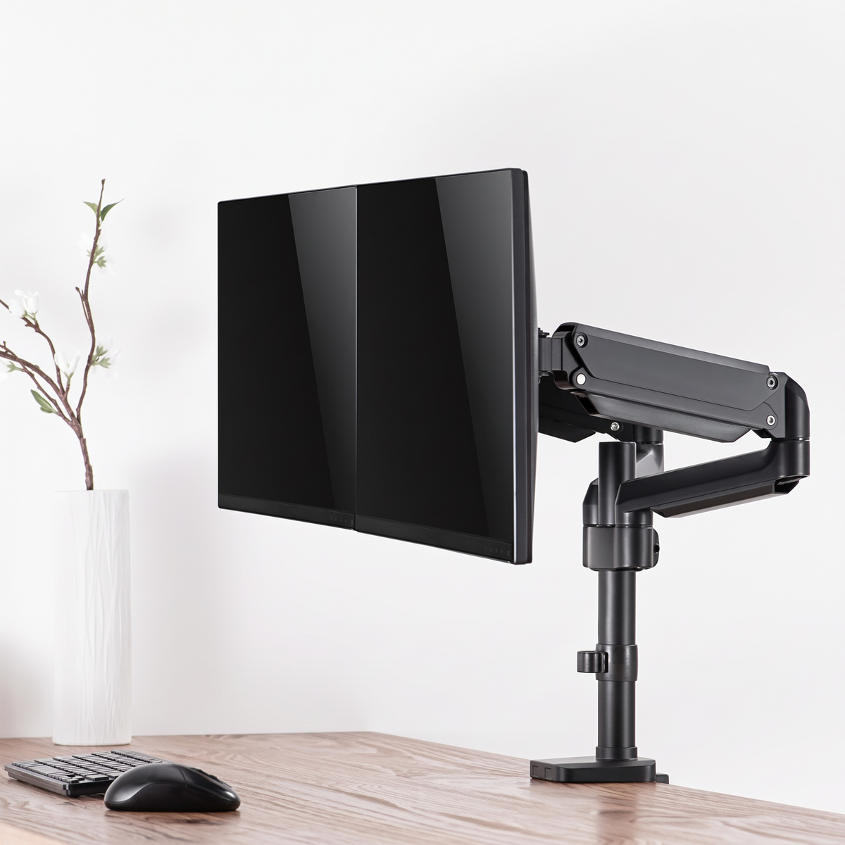 Cloud Office Studio ApexMotion matte black dual gas-spring monitor arm holding two screens on a wooden desk.