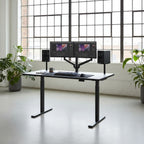 Cloud Office Studio 140cm black dual-motor standing desk with dual monitors in a bright, modern professional office.