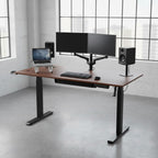 Cloud Office Studio walnut standing desk with black industrial frame, dual monitors, and laptop in a modern office.