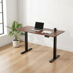 Cloud Office Studio walnut standing desk with black industrial frame, laptop, and notebook in a bright home office.